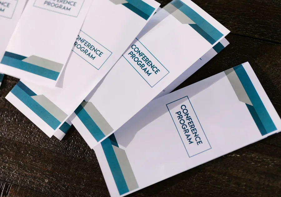 Printed event programmes fanned out on a dark wooden table.
