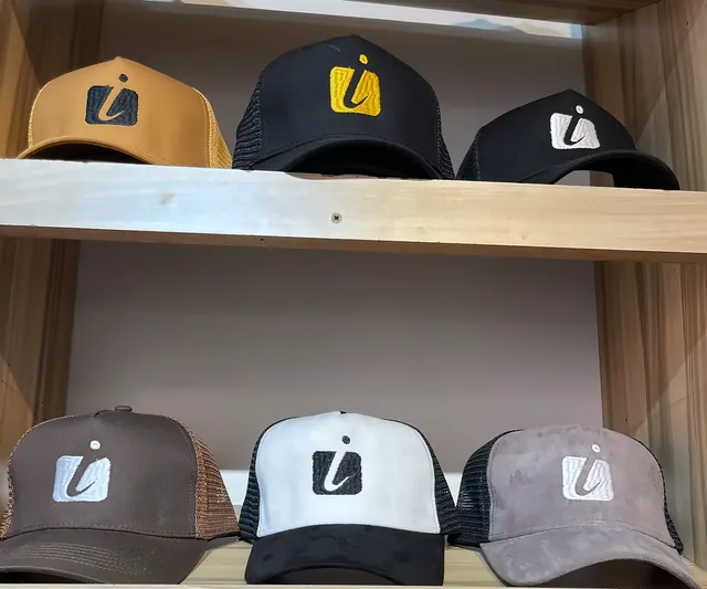 Caps embroidered with the Motion i mark on wooden shelves.
